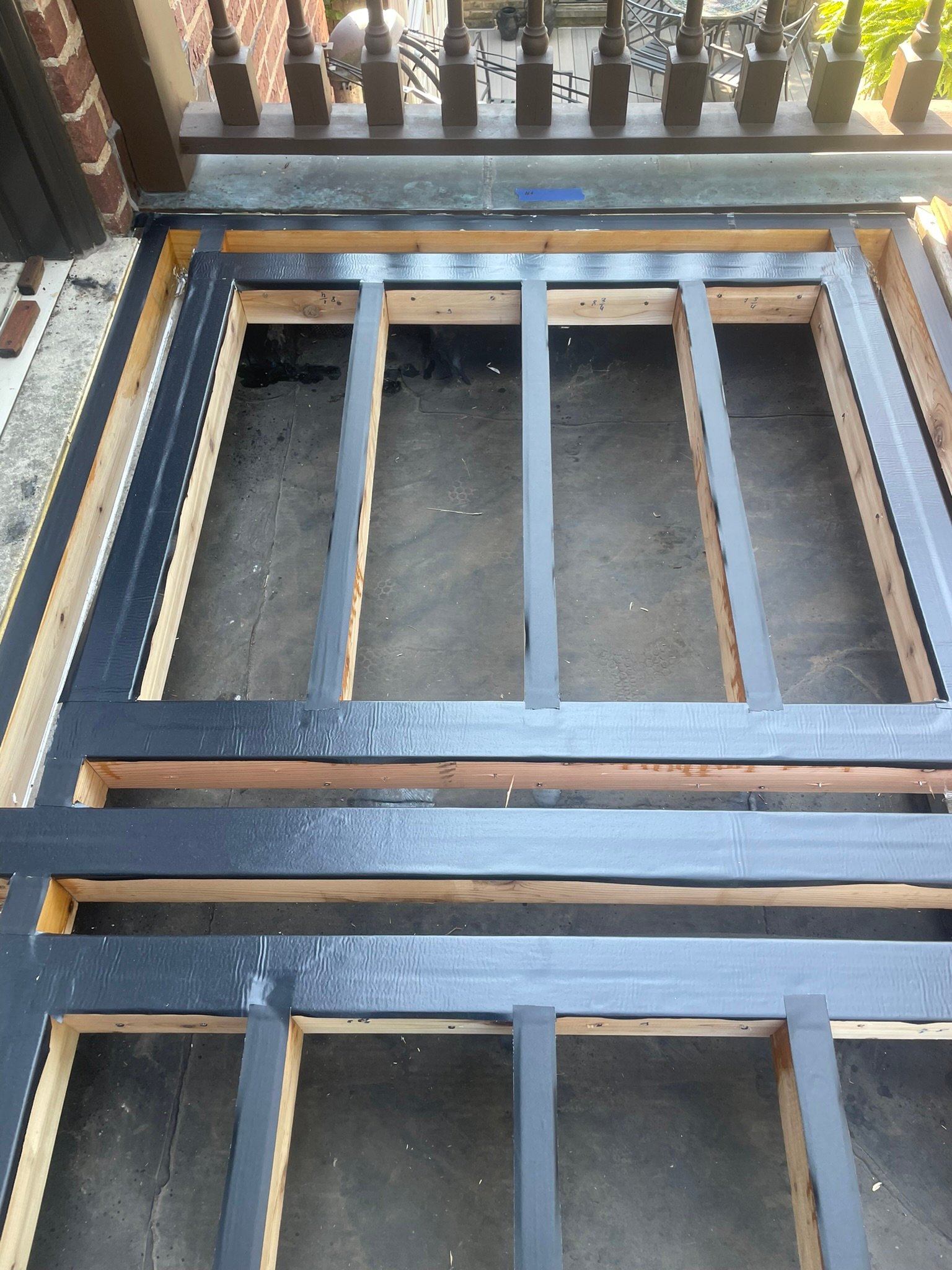 New cedar deck joists with protective joist tape during a deck frame rebuild
