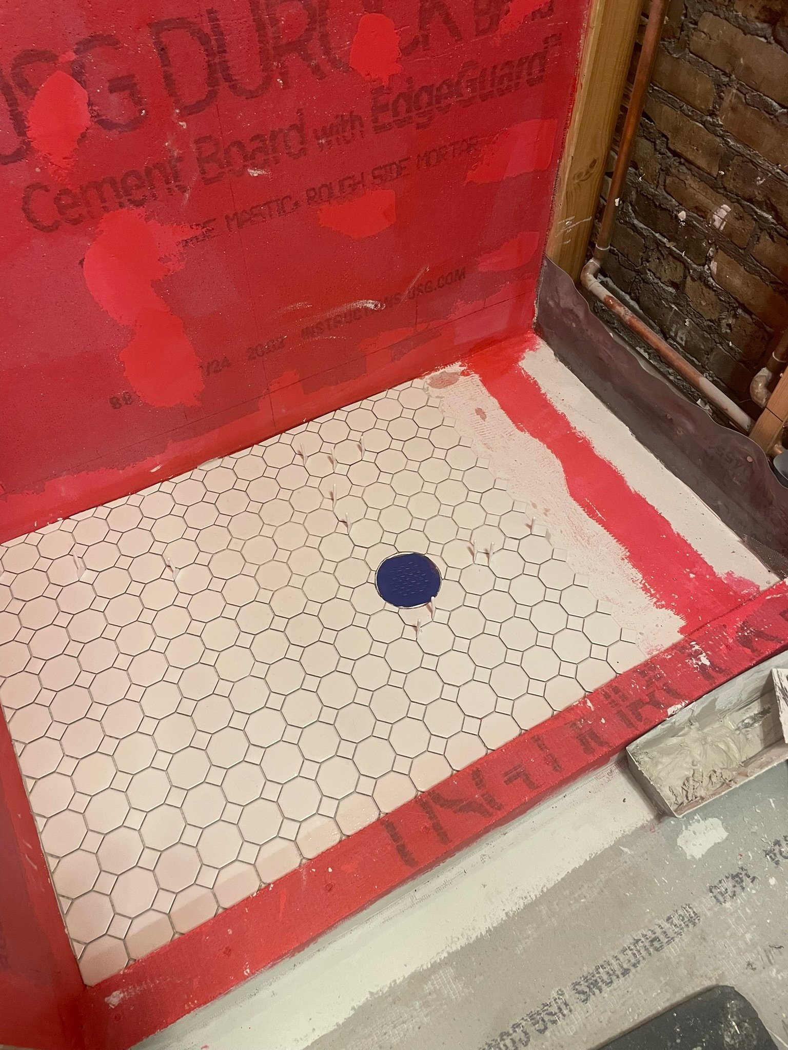 New shower pan with octagon mosaic tile over red waterproofing membrane in Mundelein IL