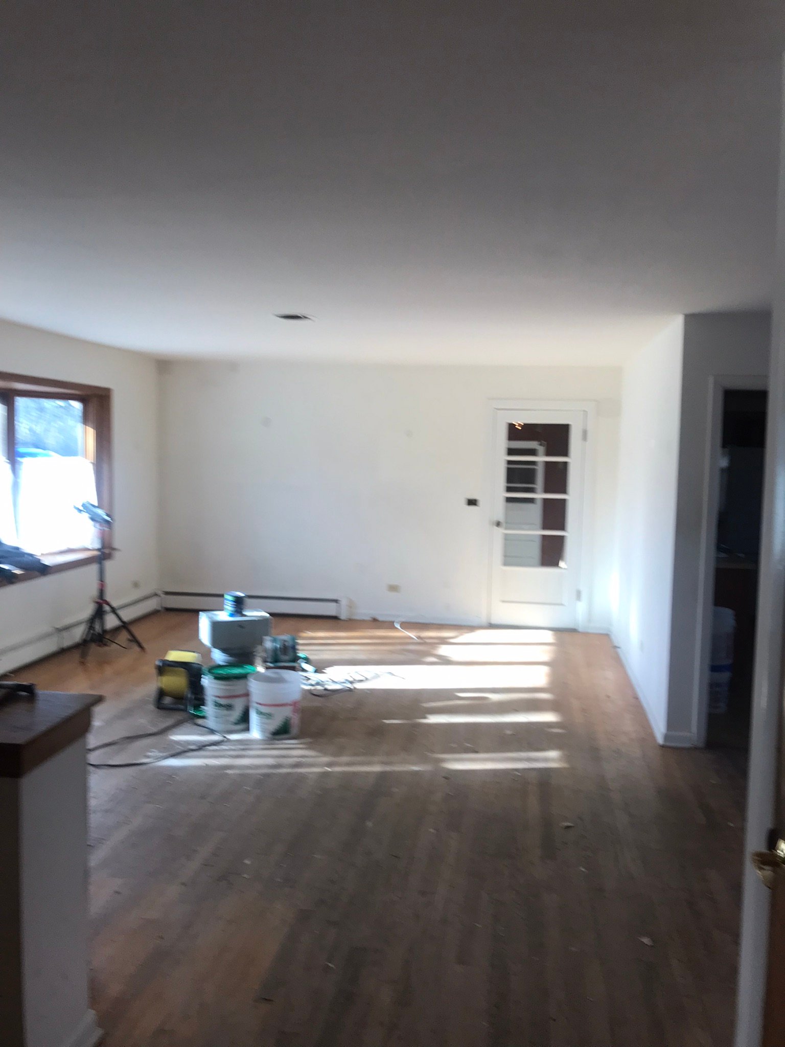 Hardwood floors being refinished in a living room during a property turnover