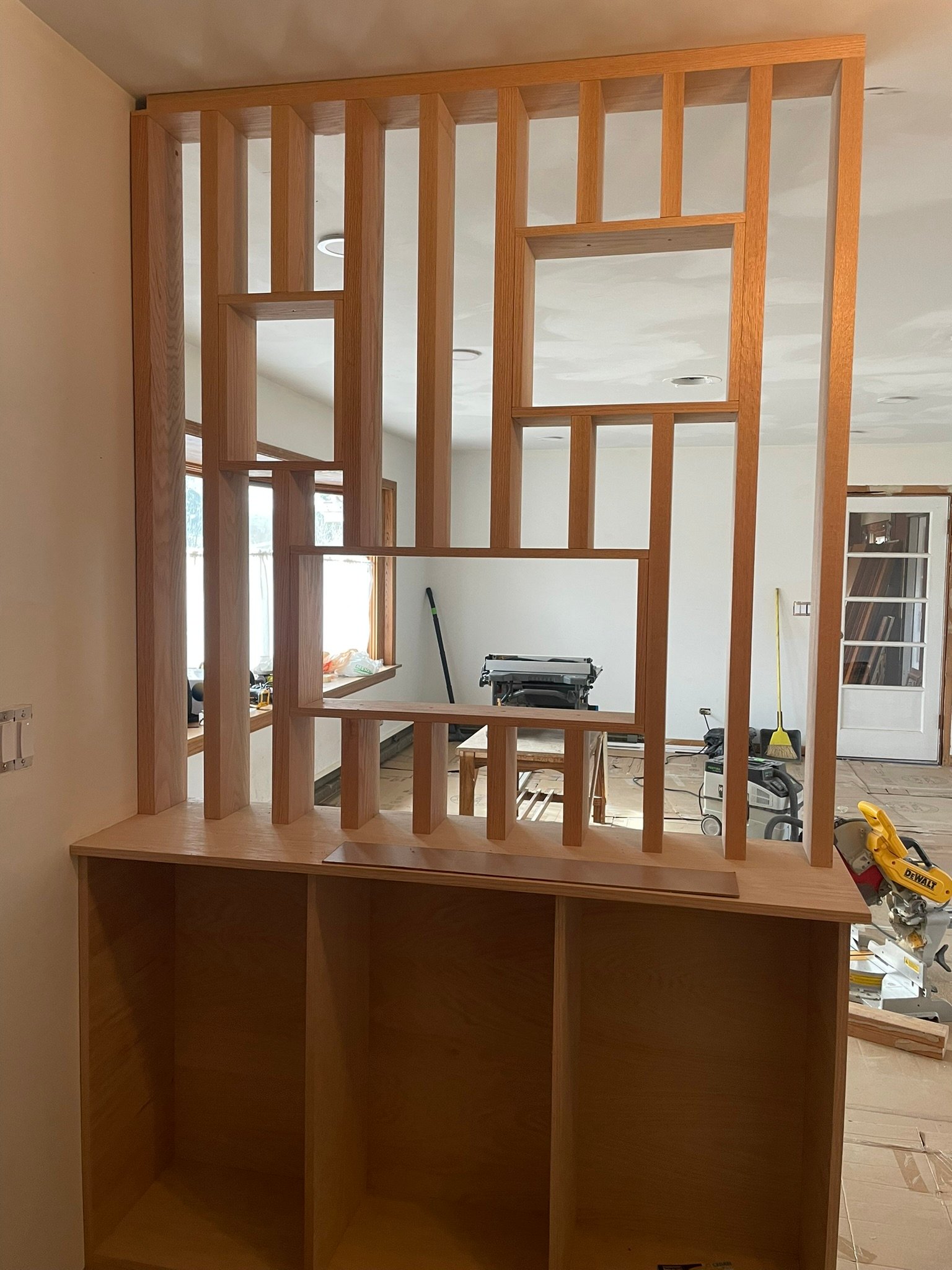 Custom oak slat room divider being built on site during an interior remodeling project