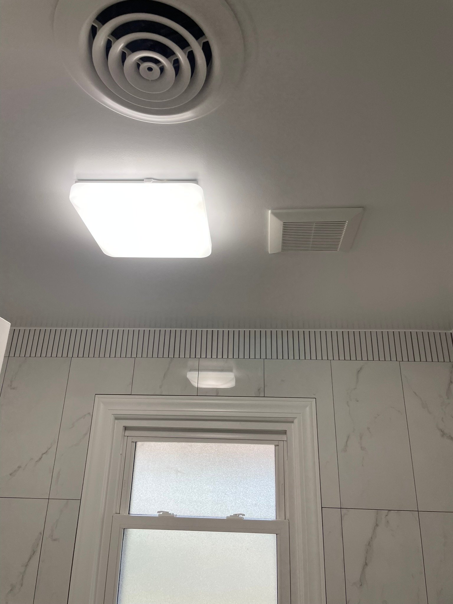 New bathroom exhaust fan and LED light installed in a ceiling by a Lake County handyman