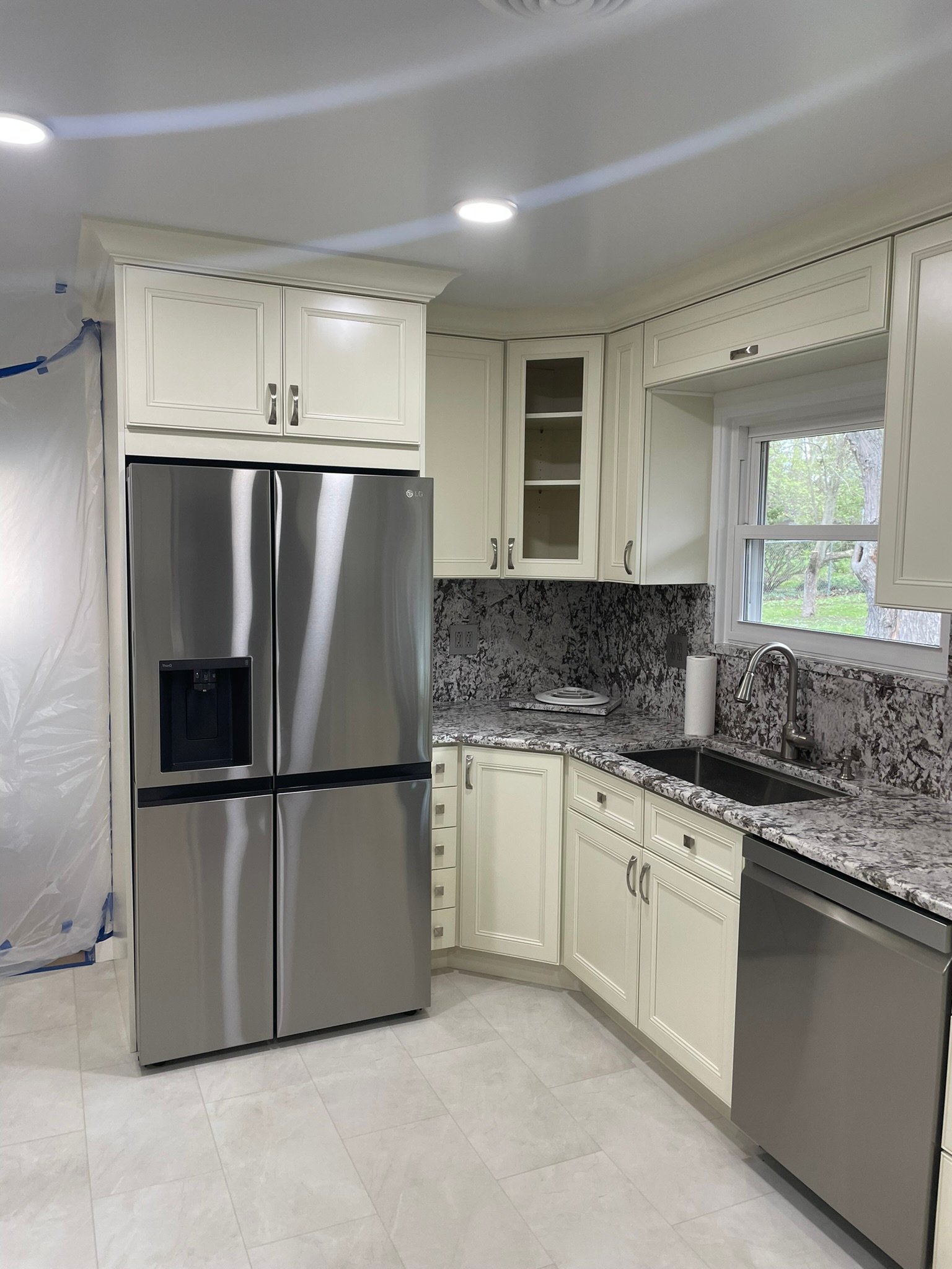 Remodeled kitchen with cream cabinets, granite countertops and full granite backsplash