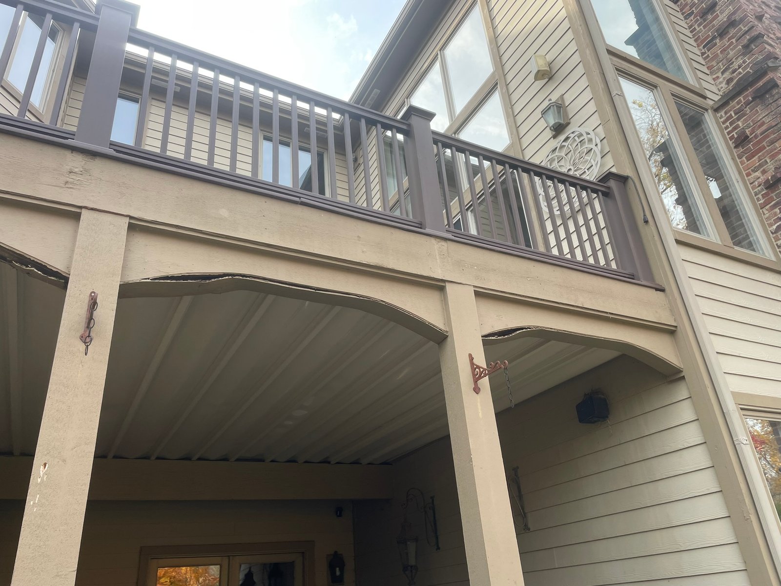 Peeling paint and wood rot on an arched balcony fascia before exterior repair