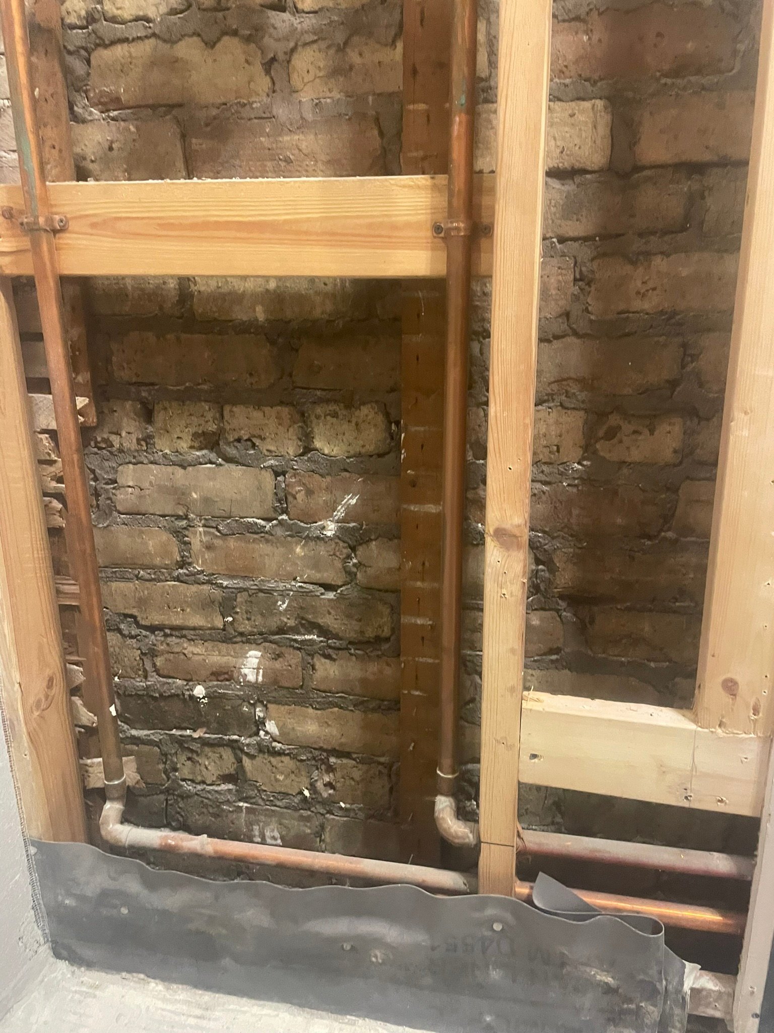Bathroom demolition exposing brick and an old lead shower pan during a remodel in Mundelein IL
